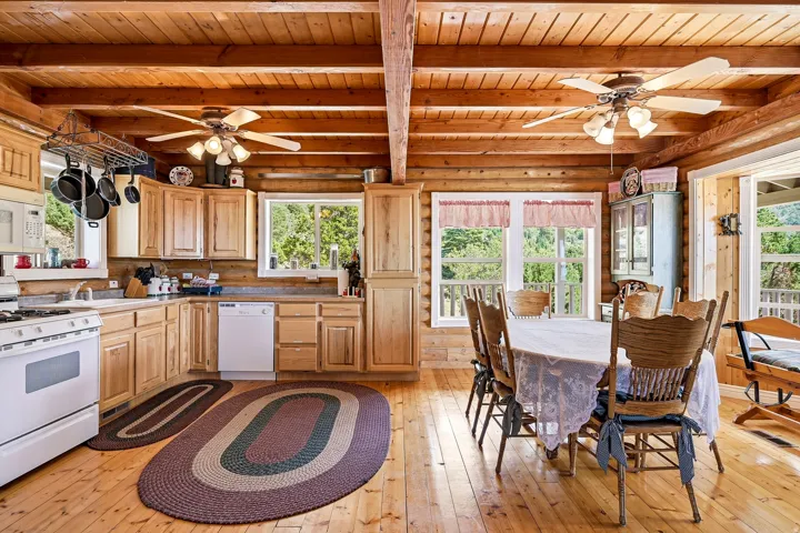 Wood-finish flooring, exposed wood beam ceiling, wood-paneled walls, built-in wood cabinetry, and white appliances