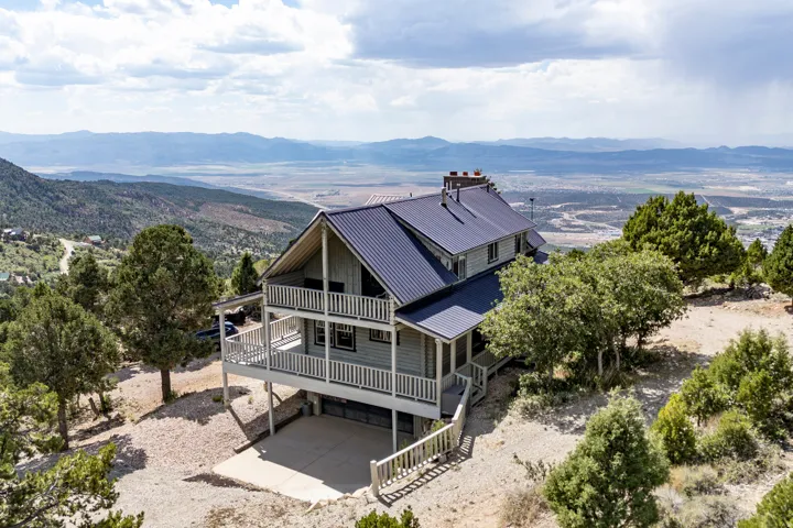 Multi-level property featuring a metal roof, dual balconies, and a lower-level concrete patio