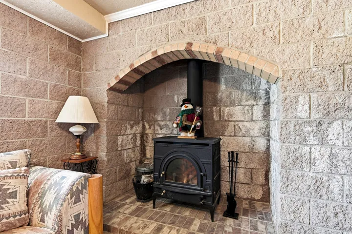 Stone block walls featuring an arched brick fireplace surround, wood-burning stove, and brick hearth