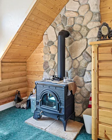 Cast iron wood-burning stove with a stone hearth, set against a stone accent wall