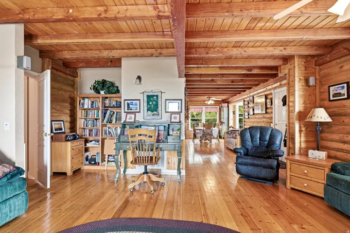 Open-concept living space showcasing exposed wooden beam construction and vaulted ceilings throughout