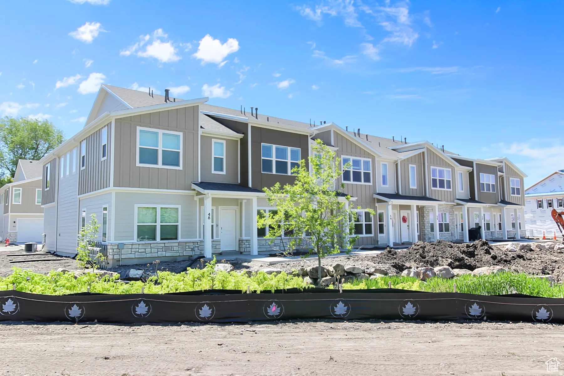 Modern townhome exterior with mixed material siding, white trim, and stone accents