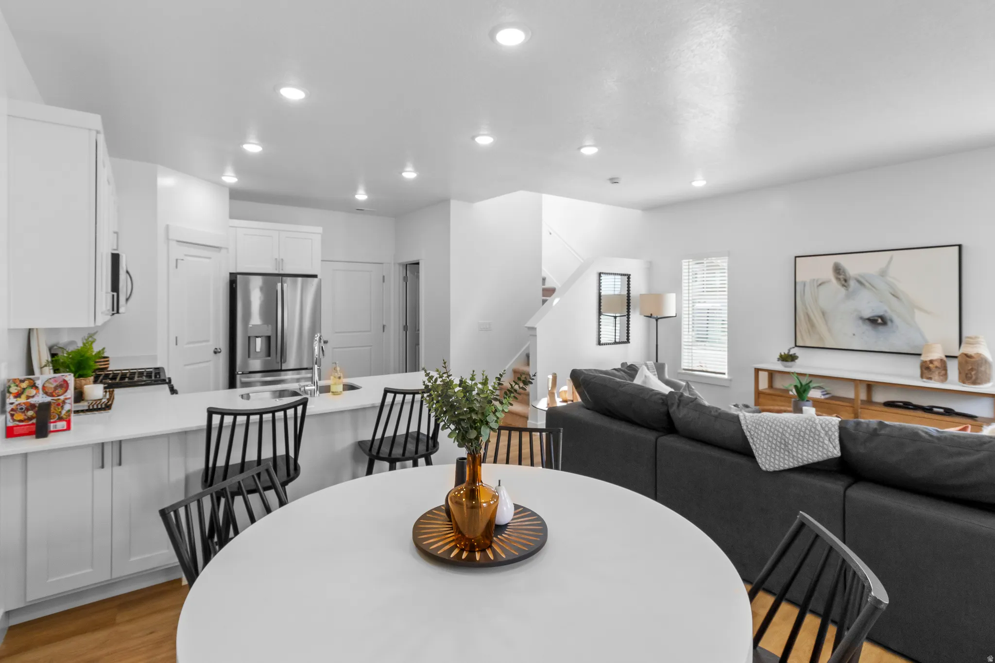 Open-concept living area featuring a kitchen island with seating, stainless steel appliances, and wood-finish flooring