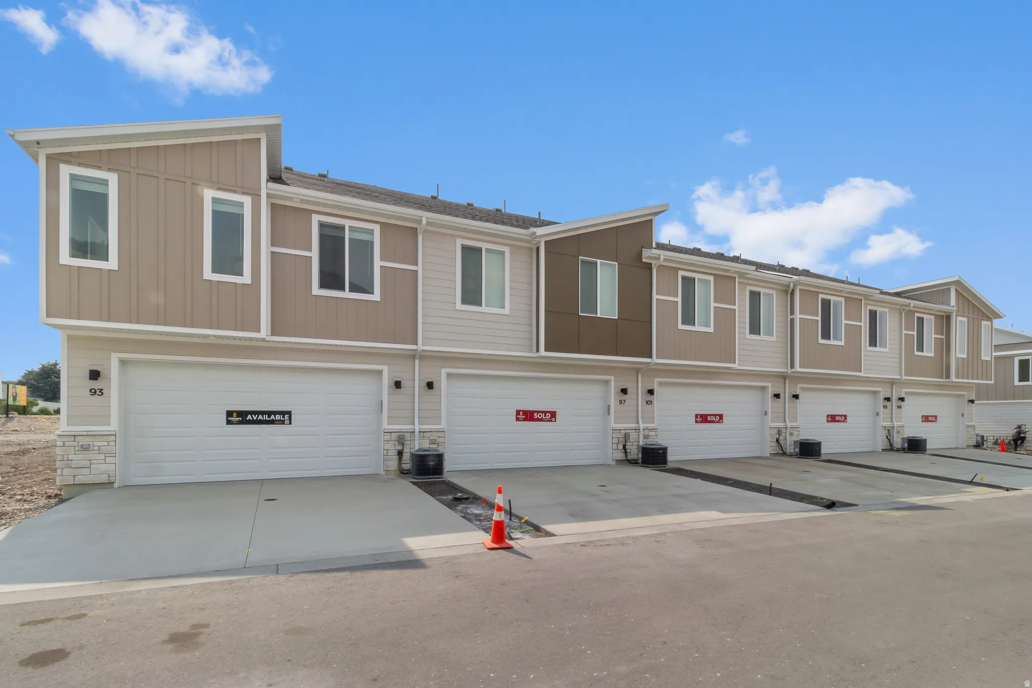 Contemporary townhome exterior with mixed material facade, individual garage access, and concrete driveways
