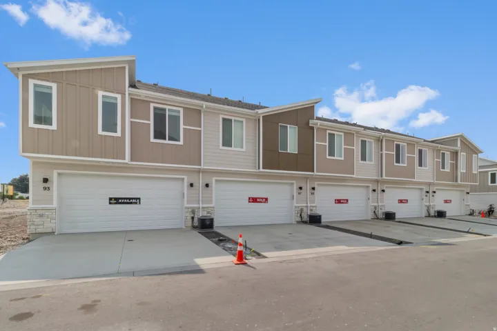 Contemporary townhome exterior with mixed material facade, individual garage access, and concrete driveways