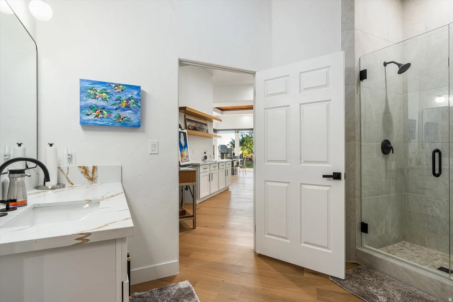 Walk-in shower with glass enclosure, single vanity with a quartz-finish countertop, and wood-finish flooring
