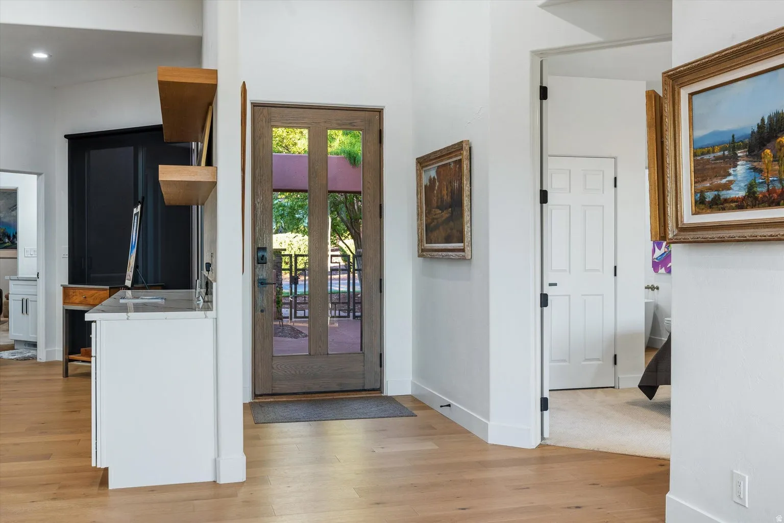 Wood-finish flooring, white walls, and a wood-panel entry door with glass inserts