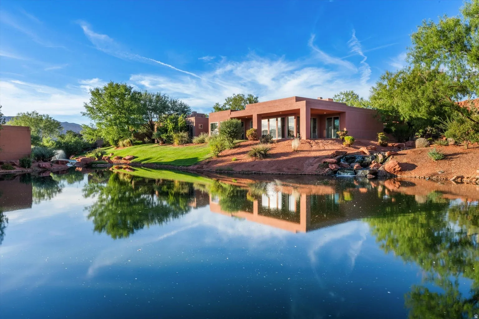 Red rock landscaping with mature vegetation and water features