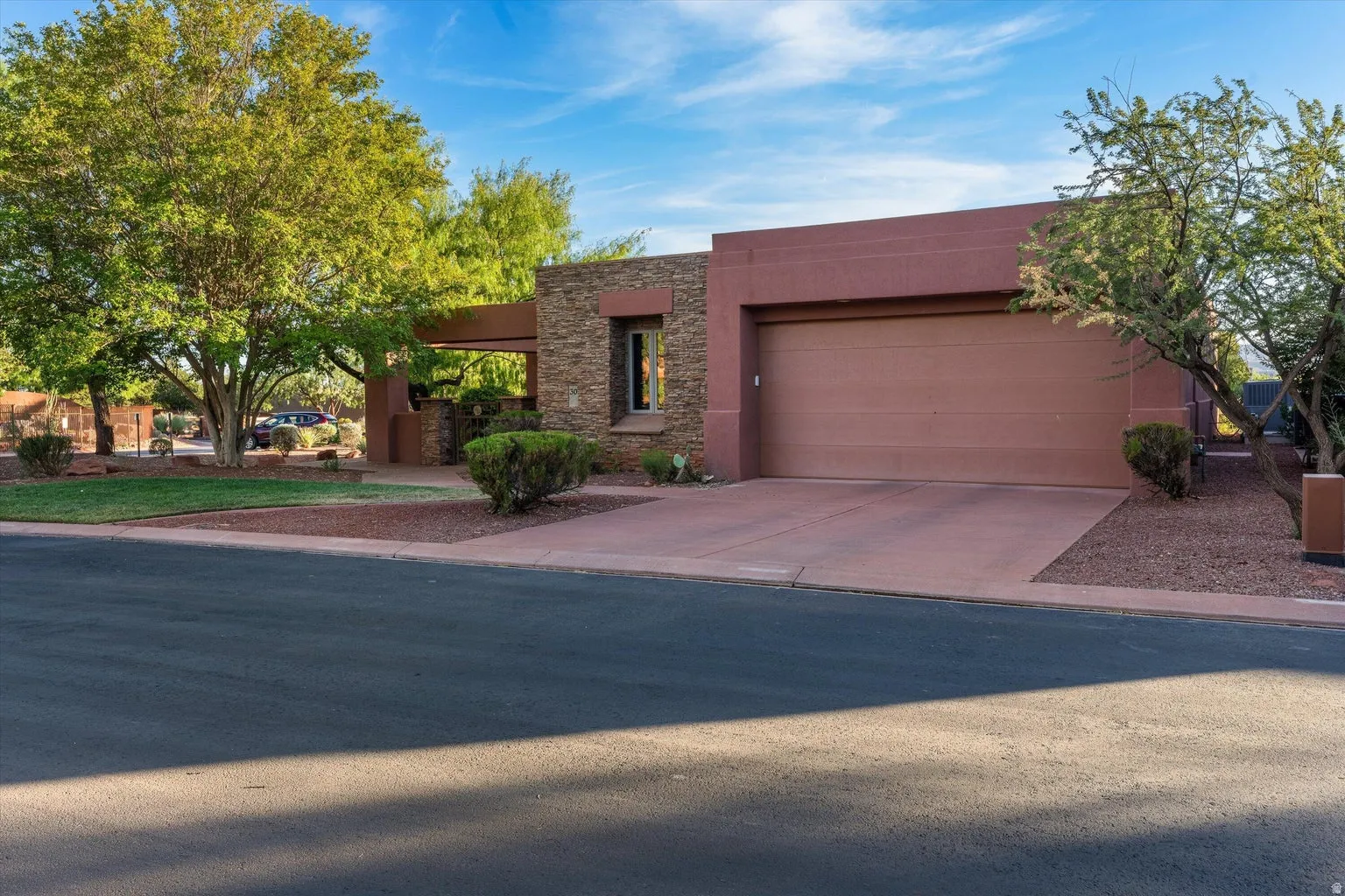 Stucco exterior with stone accents, integrated garage, and mature landscaping