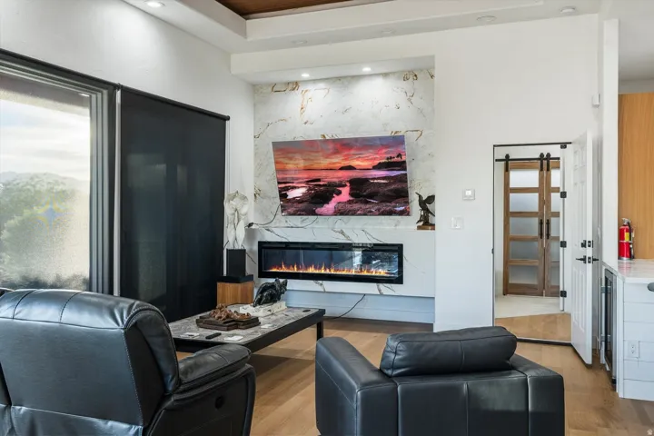Hardwood-style flooring, a built-in fireplace, a stone-clad accent wall, recessed lighting, and a sliding glass door