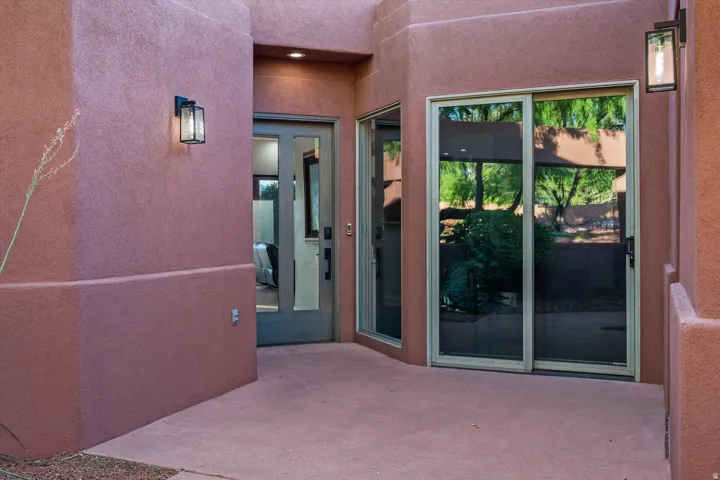 Paved exterior patio with sconce lighting, stucco exterior, and sliding glass doors