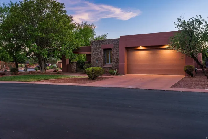 Desert modern exterior with a wood-finish garage door, stone accents, and a covered entry