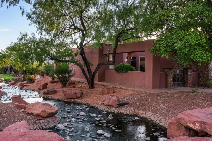 Southwestern-style exterior with a stucco finish, stone accents, and mature trees