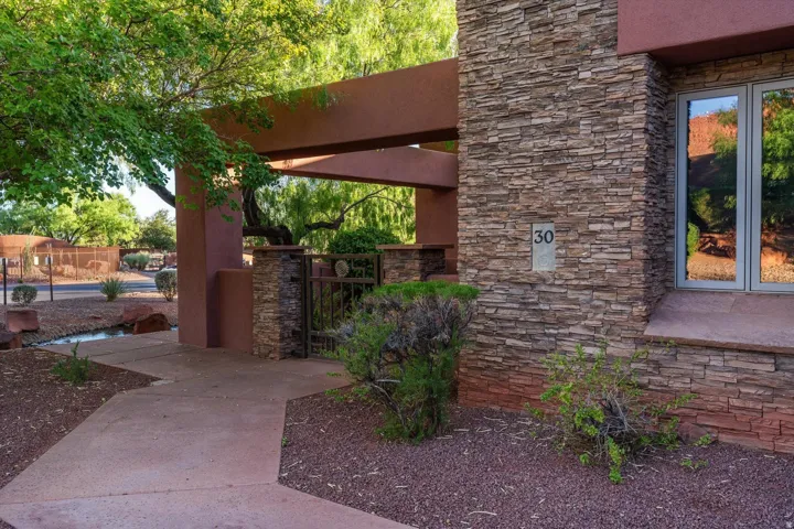 Stacked stone exterior facade with a contemporary window, concrete pathway, and decorative metal gate