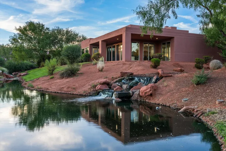 Stucco exterior with multiple glass panel doors, built-in water feature, and pond