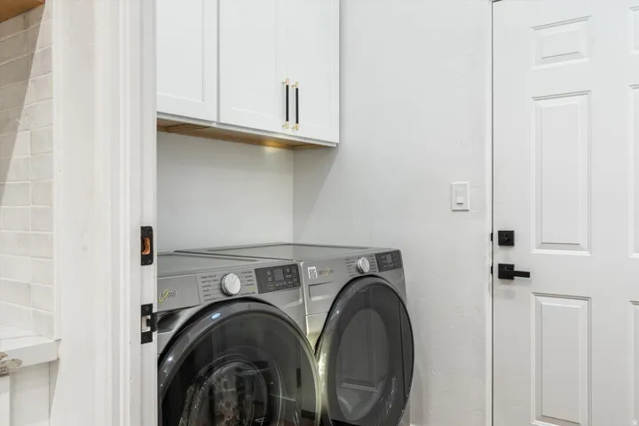 Built-in white cabinetry with gold and black hardware, wood-finish accent shelving, and a paneled door with matte black hardware