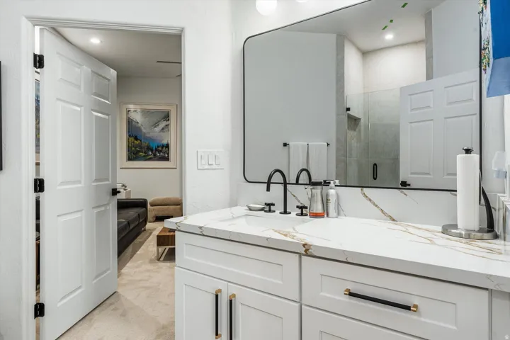 Vanity featuring a patterned countertop, matte black fixtures, and a large wall-mounted mirror
