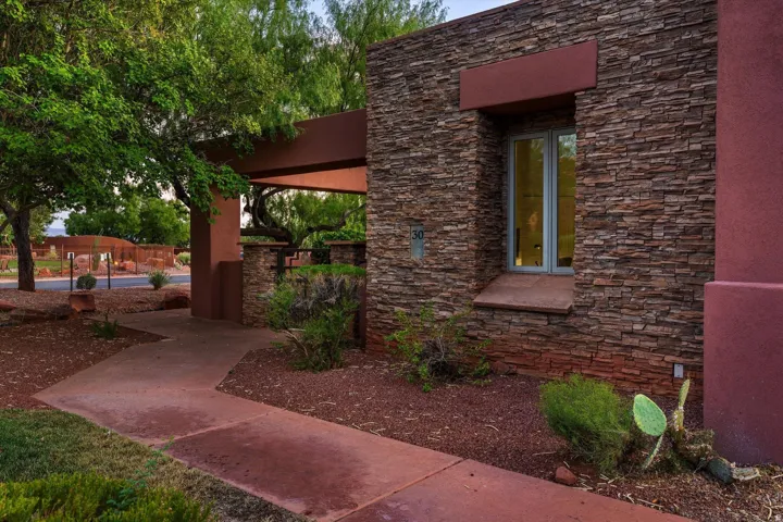 Stone veneer exterior with a prominent window, covered entryway with substantial pillars, and a concrete pathway