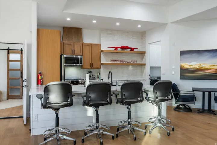 Kitchen featuring a breakfast bar with white shiplap paneling and a light-toned countertop, stainless steel appliances, and a tile backsplash