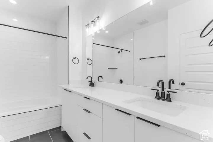 Dual sink vanity with white countertop, matte black fixtures, and white subway tile bath surround