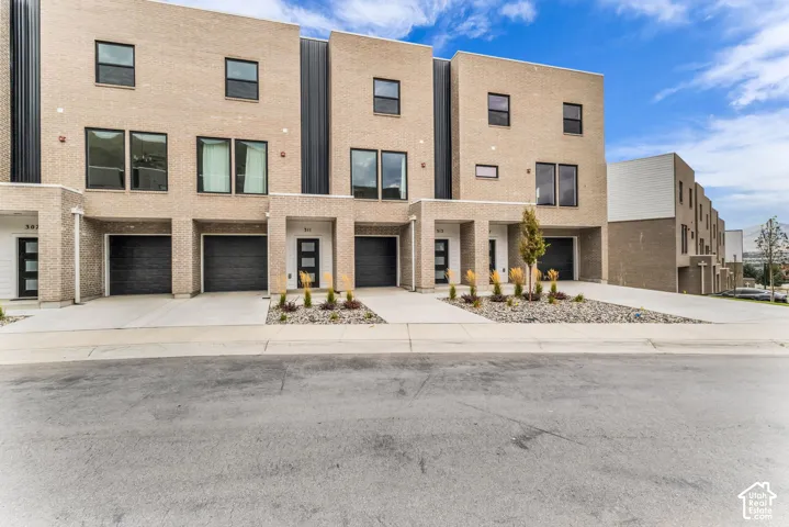 Modern townhome exterior featuring light-toned brick and dark-framed windows