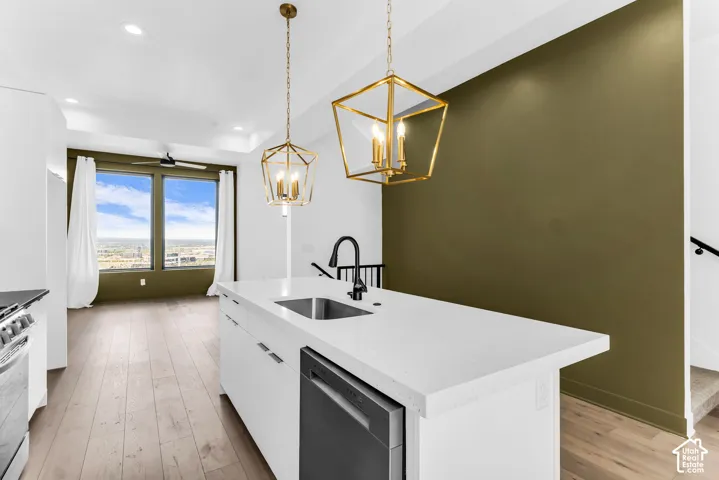 Kitchen island with integrated sink, white countertops, and stainless steel dishwasher