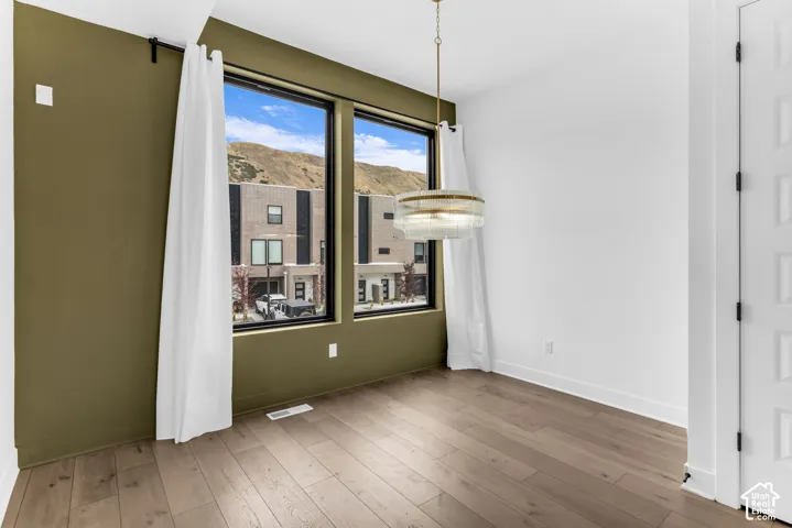 Wood-finish flooring, full-height windows, a modern chandelier, and a paneled interior door