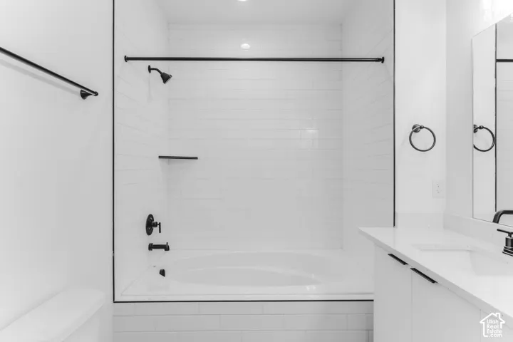 Modern primary bathroom featuring a frameless glass-enclosed shower with subway tile surround, dual vanity with circular mirror fixtures, matte black hardware accents, recessed lighting, and clean-lined cabinetry throughout