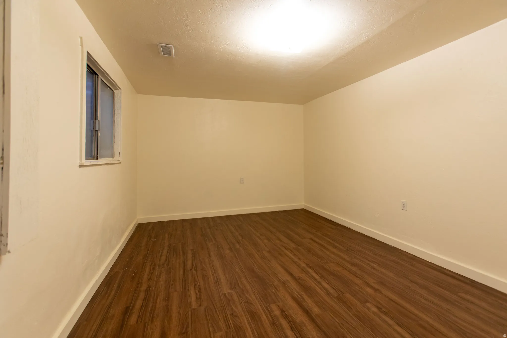 Wood-finish flooring, neutral wall tones, recessed lighting, and a single window