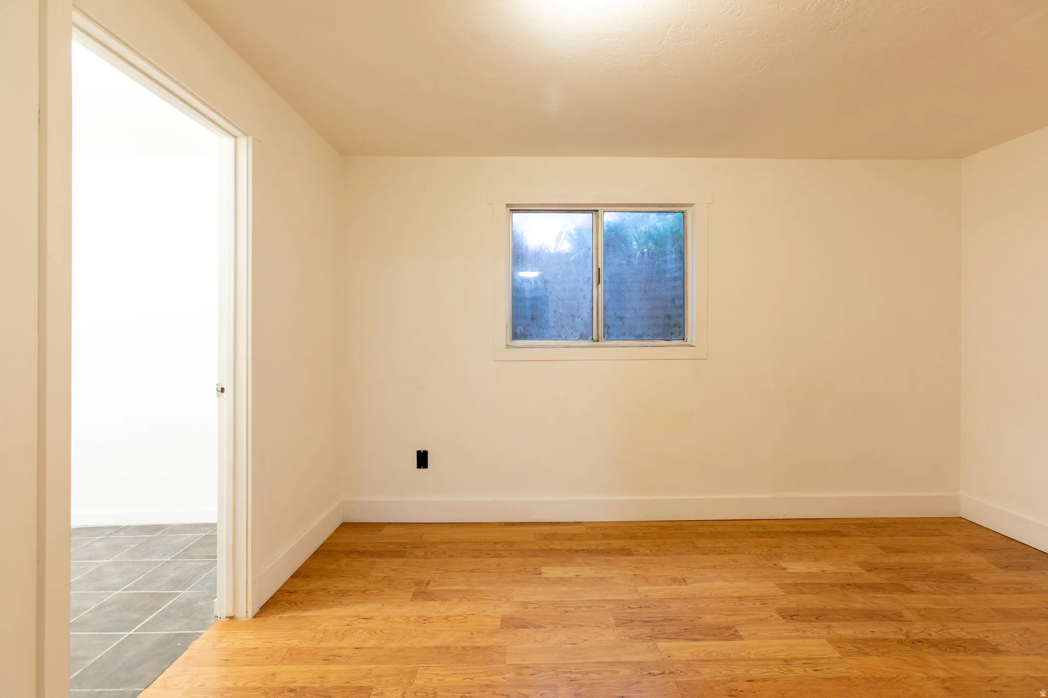 Warm neutral wall tones, wood-finish flooring, and a sliding window