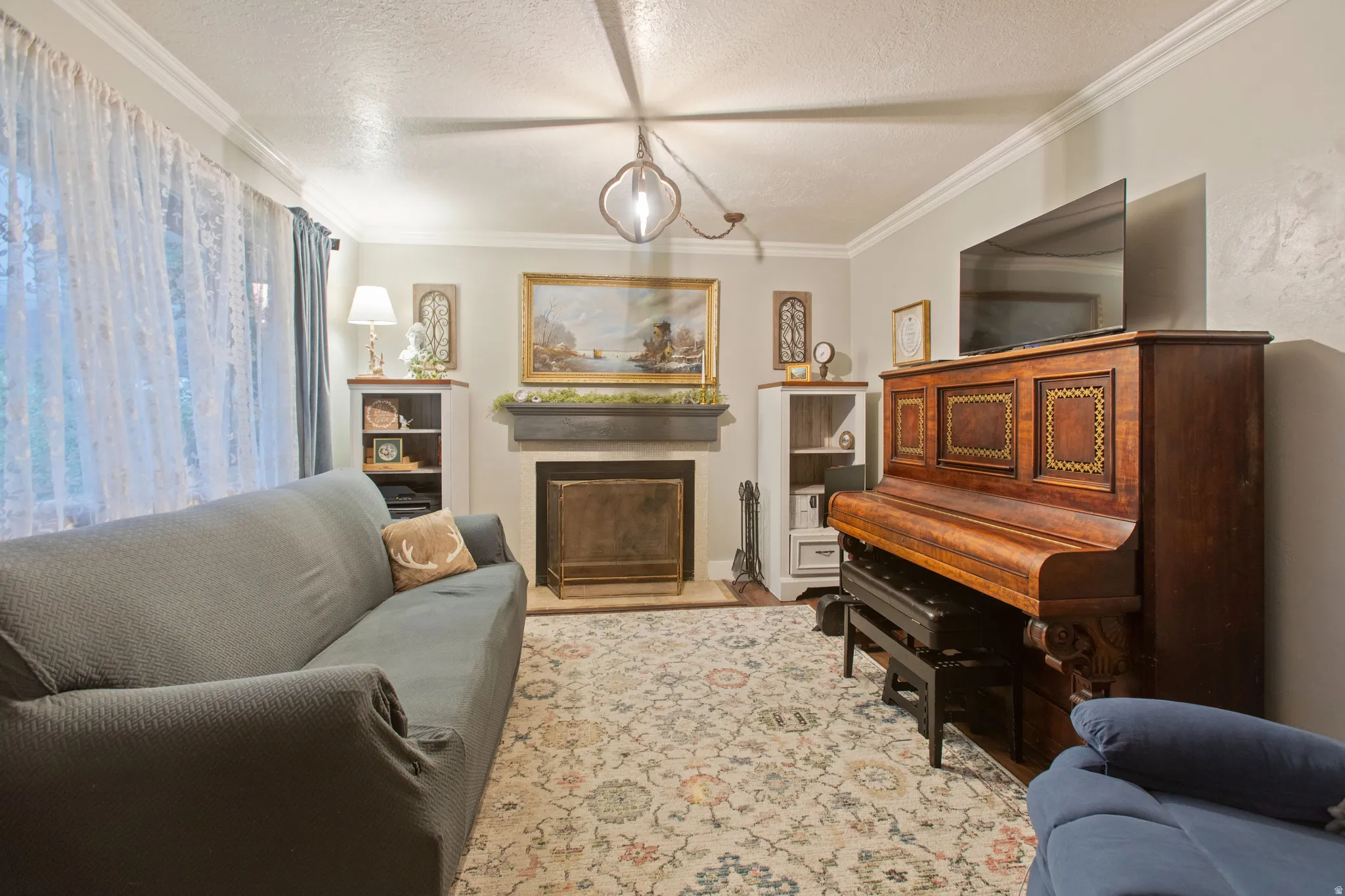 Recessed fireplace with mantel, built-in shelving, crown molding, and an attached ceiling light fixture