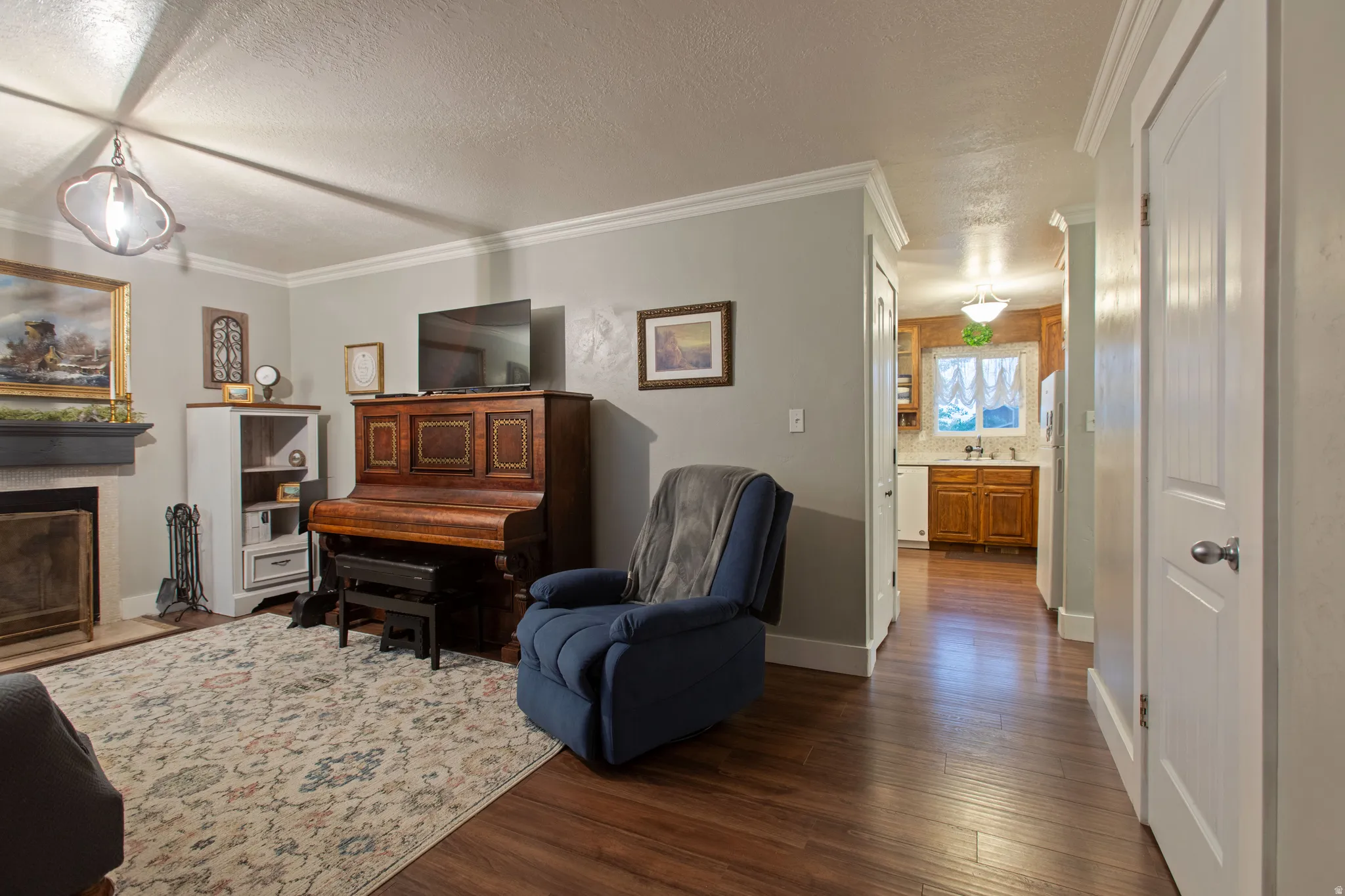 Wood-finish flooring, crown molding, and a fireplace with a mantel