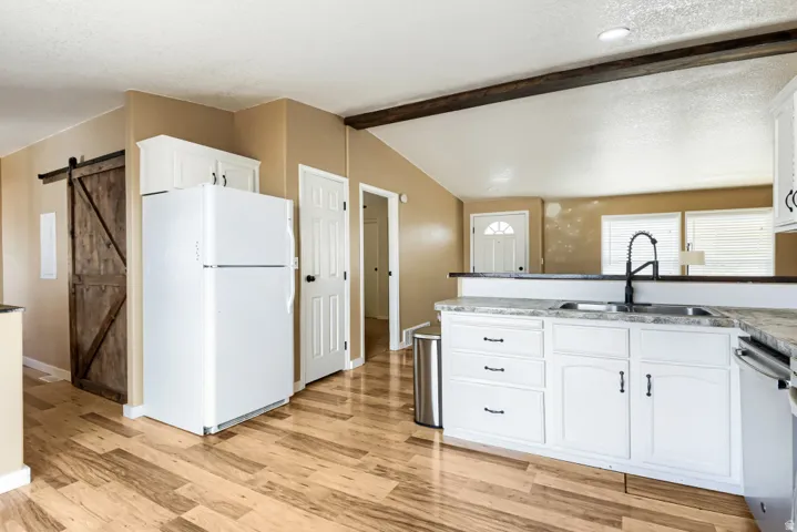 Kitchen featuring white cabinetry, gray countertop, black pull-down faucet, and wood-finish flooring
