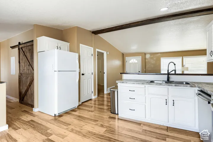 Kitchen featuring white cabinetry, gray countertop, black pull-down faucet, and wood-finish flooring