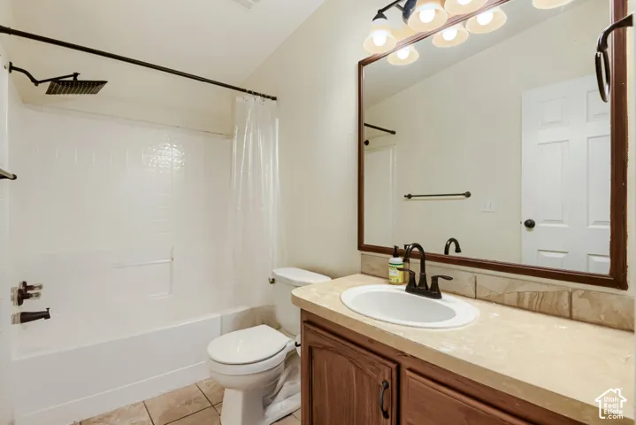 White rectangular shower/tub with a rain showerhead, single-sink vanity with a light-colored countertop, and wood-finish cabinetry