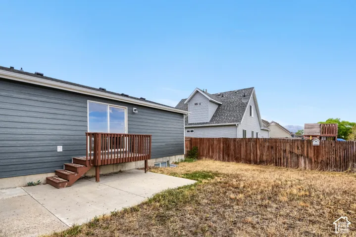 Rear exterior with horizontal siding, sliding glass door, and a wooden deck