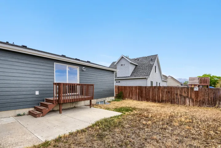 Rear exterior with horizontal siding, sliding glass door, and a wooden deck