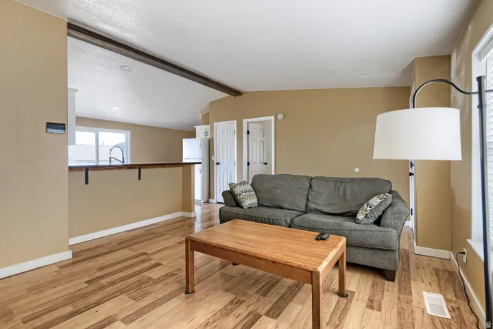Wood-finish flooring throughout, light neutral paint, white trim, and a built-in breakfast bar with iron brackets