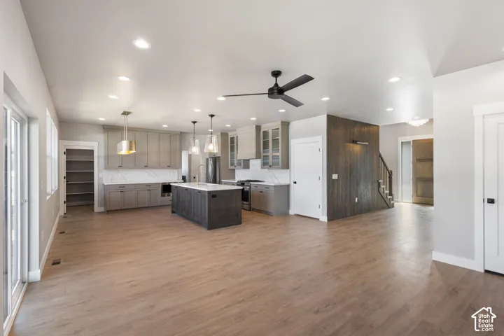 Open concept living area featuring wood-finish flooring, recessed lighting, and a modern kitchen with a center island and taupe cabinetry