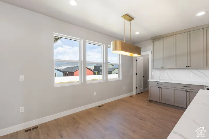 Light-colored wood-finish flooring, recessed lighting, and a modern rectangular pendant light