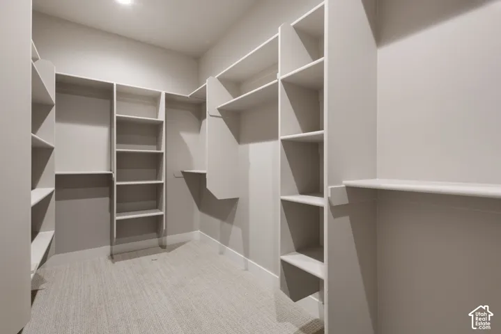 Expansive closet featuring integrated shelving, multiple hanging rods, durable carpeting, and recessed lighting