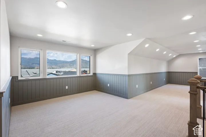 Spacious room with recessed lighting, light-toned carpet, and wainscoting