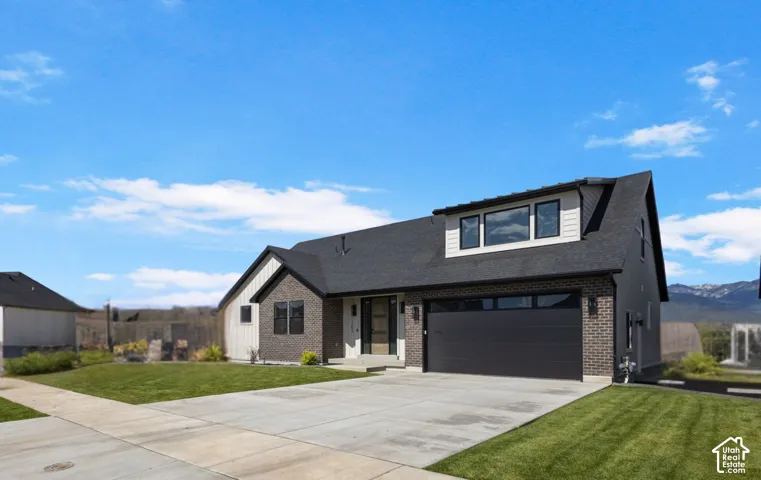 Contemporary architectural design featuring a mixed-material facade, an attached garage, a dormer with multiple windows, and a concrete driveway