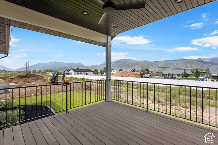 Expansive covered deck with composite wood-look decking, black metal railings, and an outdoor ceiling fan
