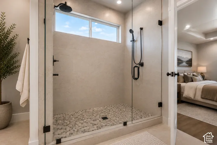 Frameless glass shower with black fixtures and pebble-finish floor