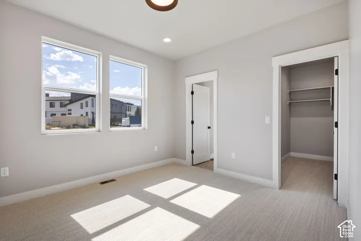 Two vertical windows, light gray walls, light-toned carpet, recessed lighting, and a closet with shelving
