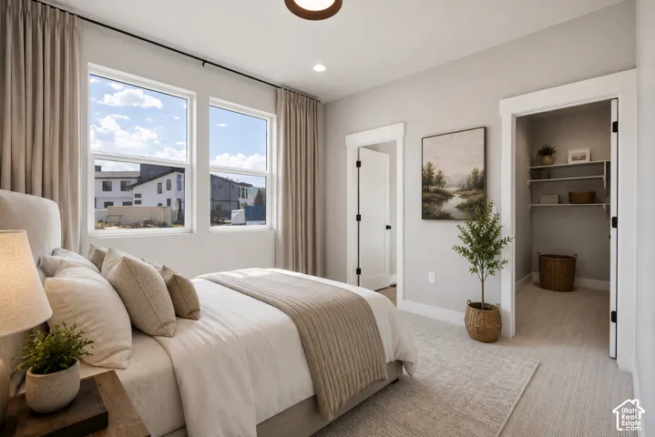 Recessed lighting, wood-finish ceiling light fixture, two tall windows with light-toned  carpeted flooring, and a walk-in closet with built-in shelving