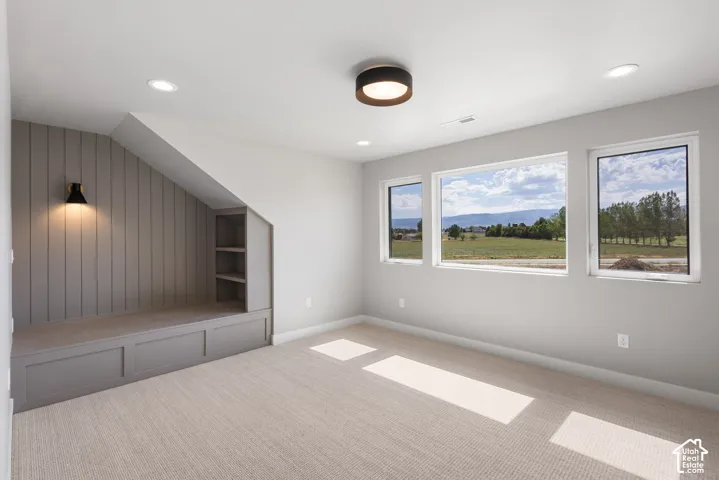 Built-in seating with integrated shelving, accent wall paneling, three large windows, recessed ceiling lighting, and a flush-mount ceiling fixture