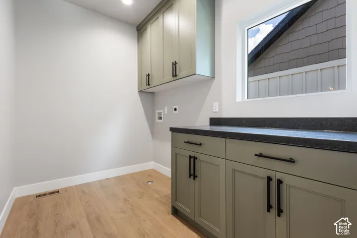 Wood-finish flooring, recessed lighting, built-in cabinetry with matte black hardware, dark countertop, and a white-framed window