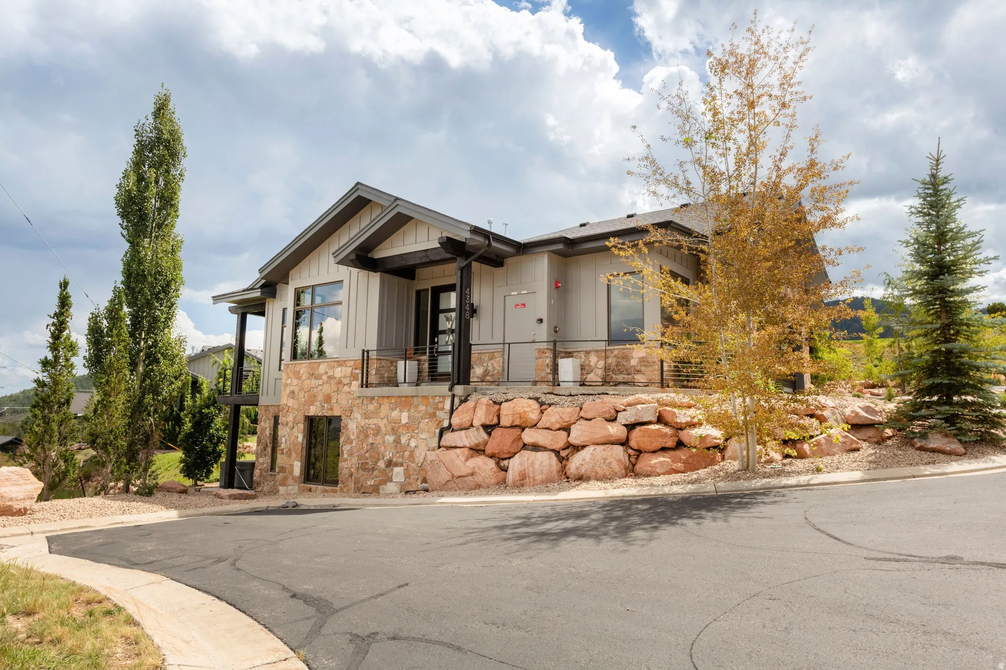 Contemporary exterior with stone facade, board and batten siding, dark trim accents, and a covered entry